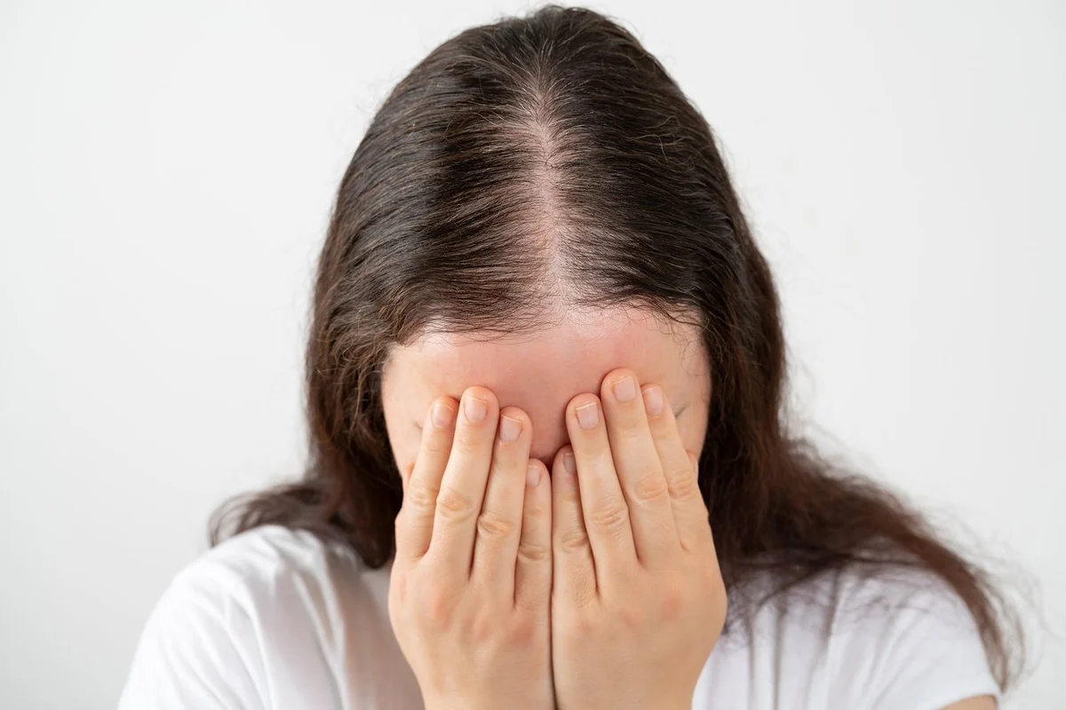 Woman stressed and crying over rapid hair loss