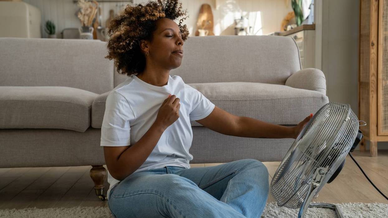 woman suffering from a hot flash, sitting on the floor at home