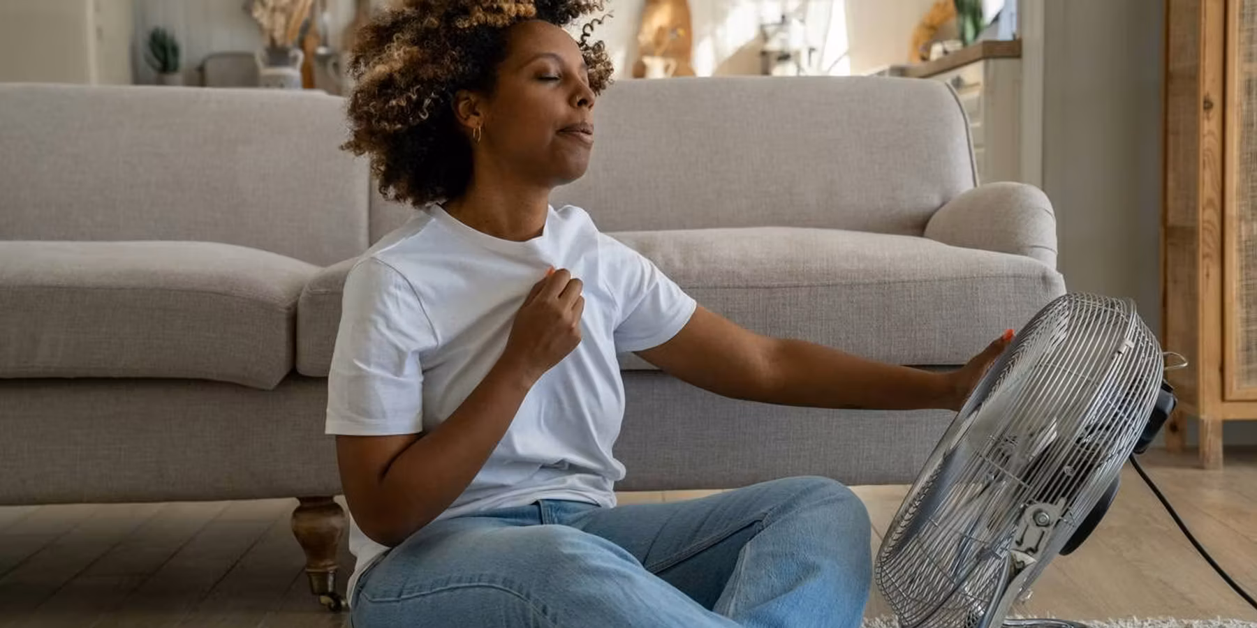 woman suffering from a hot flash, sitting on the floor at home