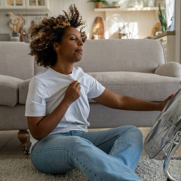 woman suffering from a hot flash, sitting on the floor at home