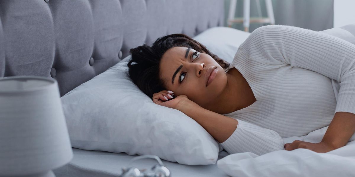 woman suffering from insomnia, lying in bed, waking up throughout the night