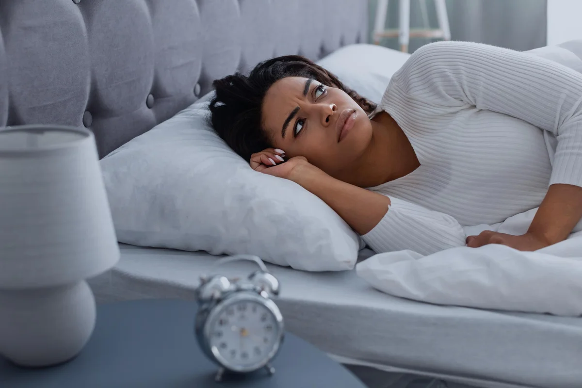 woman suffering from insomnia, lying in bed, waking up throughout the night