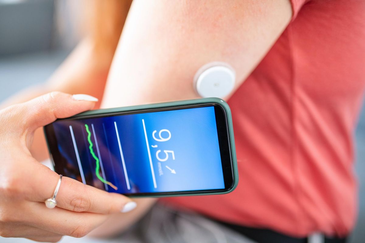 Woman Swiping Glucose Sensor with Phone for Measurement