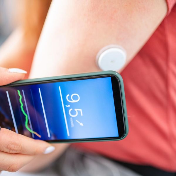 Woman Swiping Glucose Sensor with Phone for Measurement