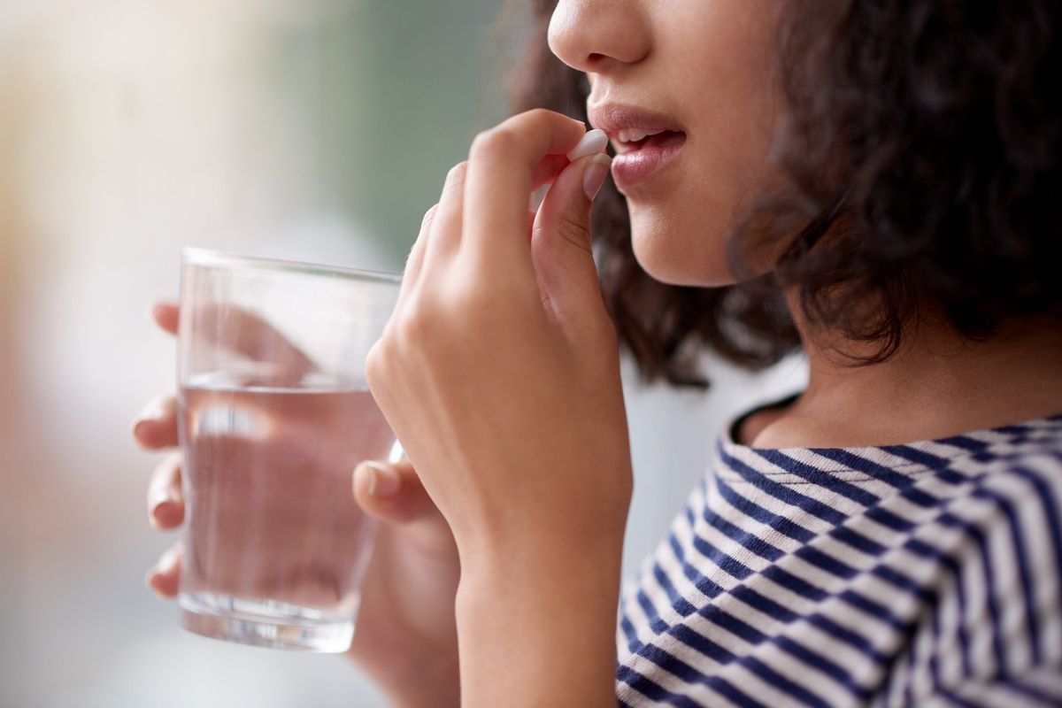 woman taking a pill with water