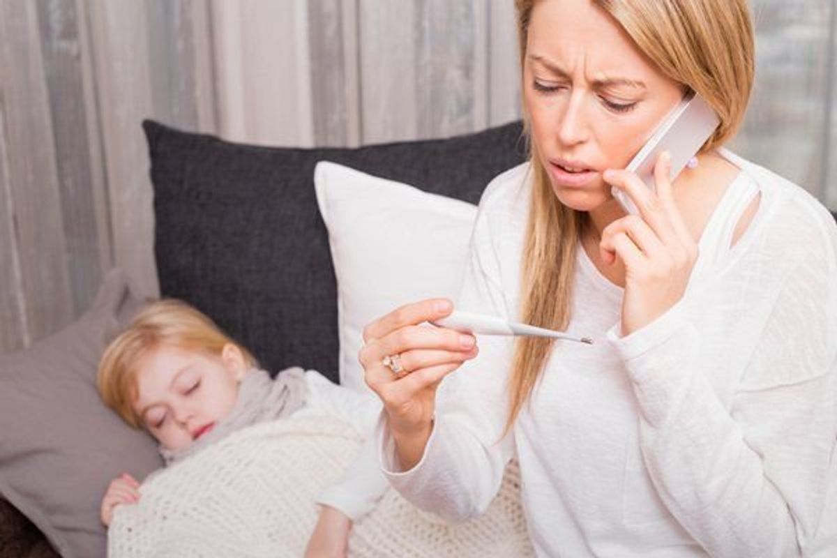 woman taking child's temperature