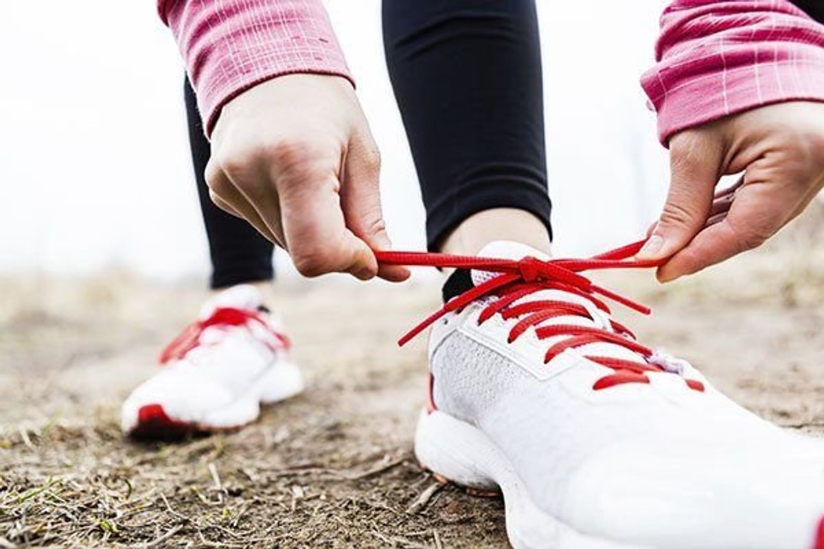 woman tying her shoelaces on her running sneakers