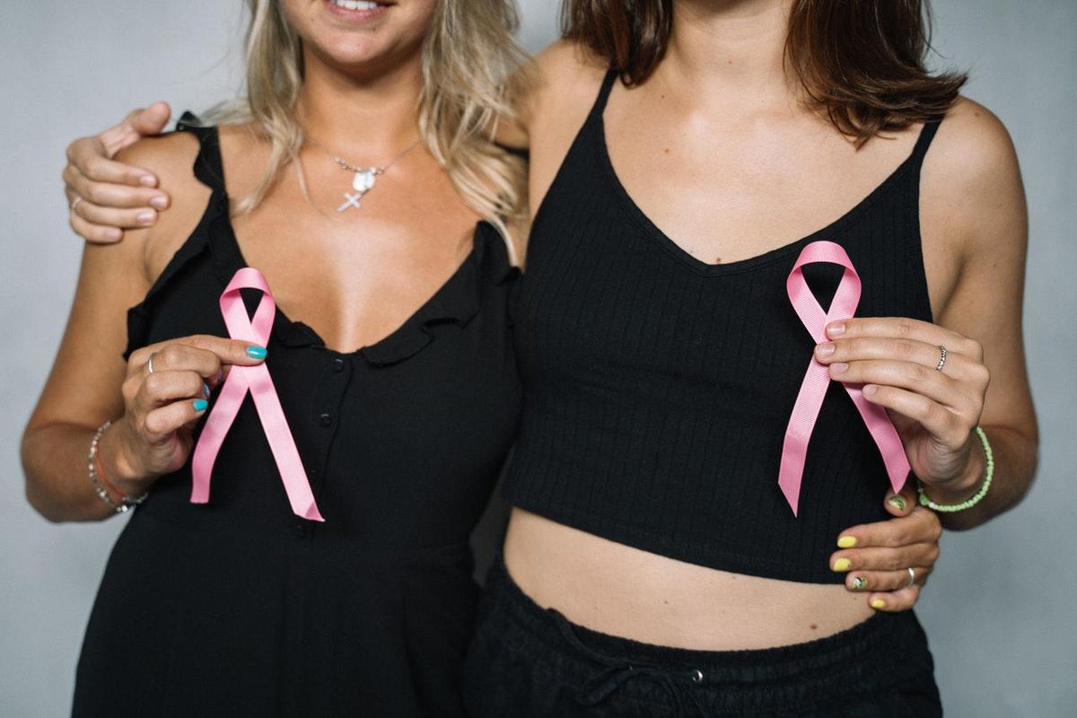 woman wearing black clothes holding breast cancer awareness ribbons
