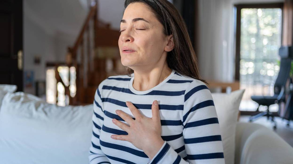 Woman With A Panic Attack Having Trouble Breathing Sitting On Sofa At Home