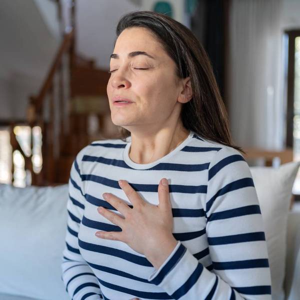 Woman With A Panic Attack Having Trouble Breathing Sitting On Sofa At Home