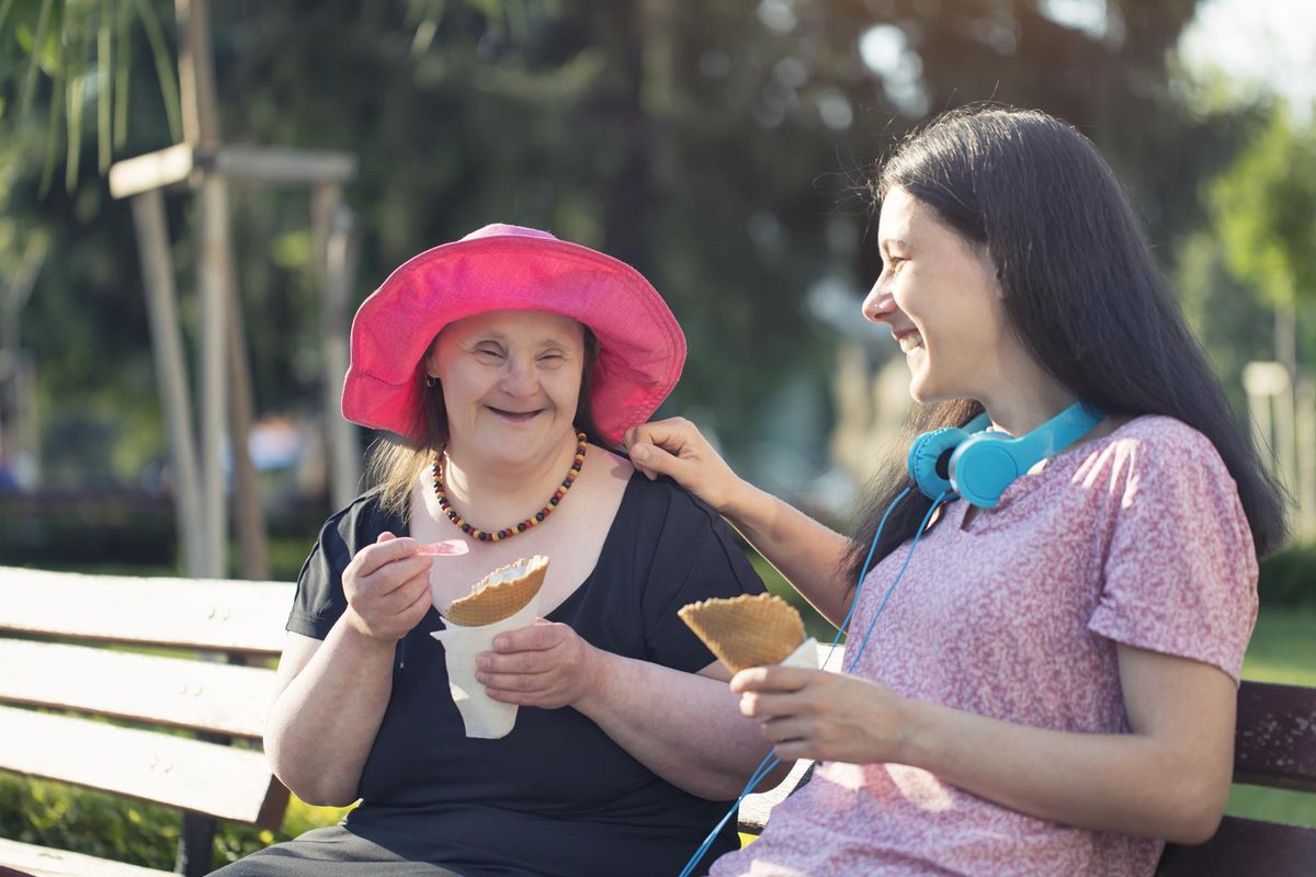 Woman with Down Syndrome and her sister eating ice cream and having fun in a park.