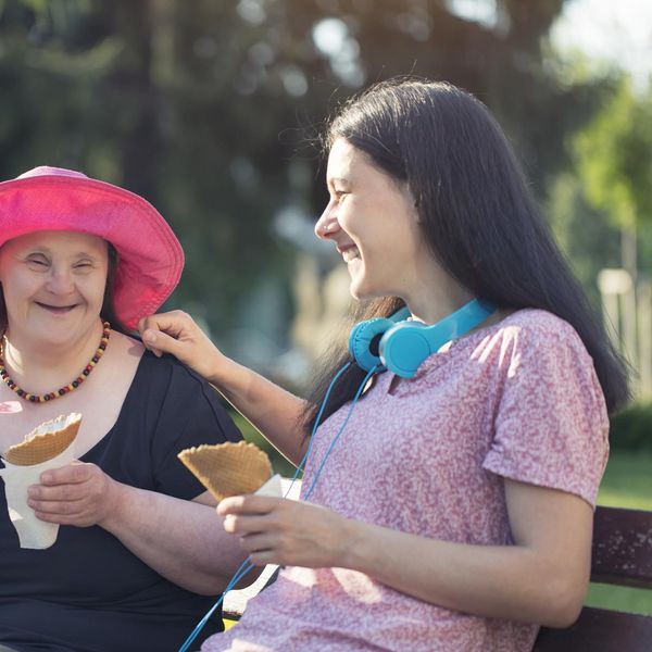 Woman with Down Syndrome and her sister eating ice cream and having fun in a park.