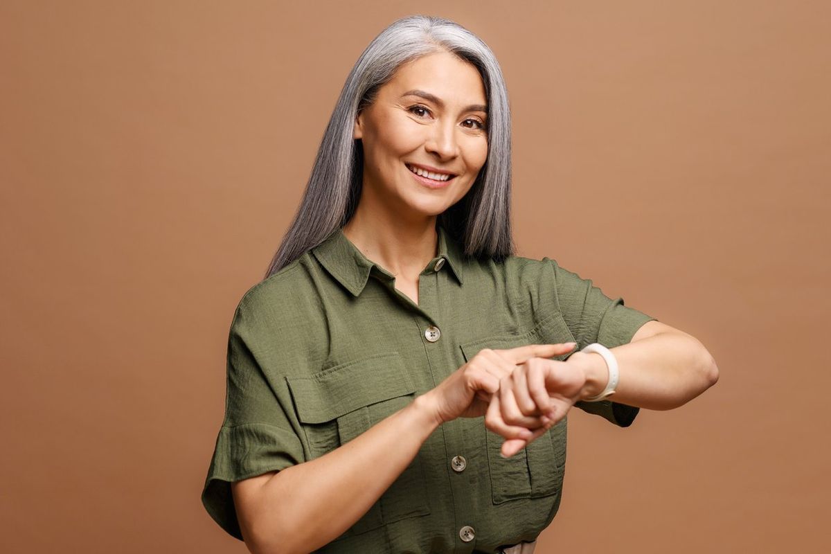 woman with grey hair wearing casual clothes In hurry pointing to watch