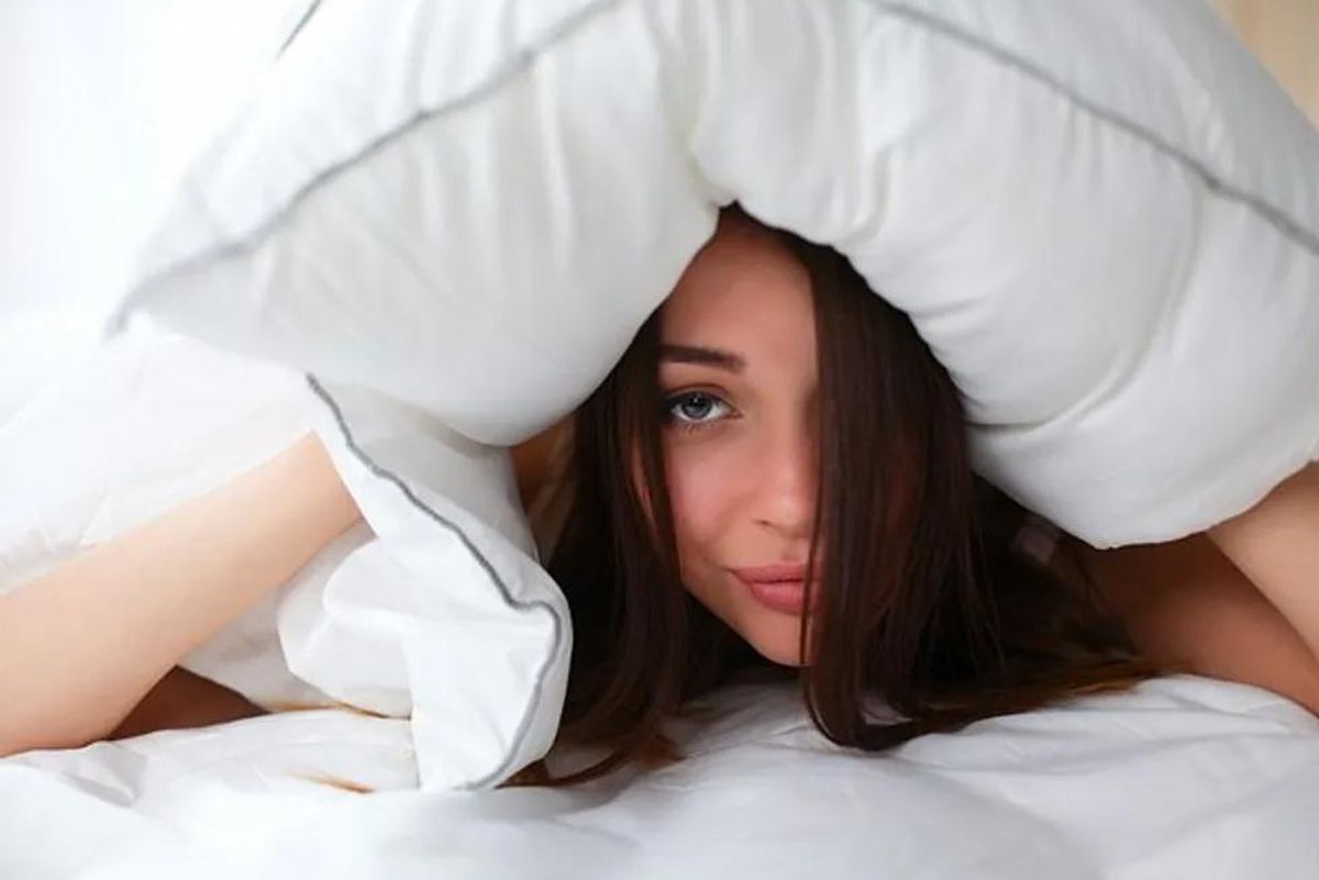 woman with her head under a pillow