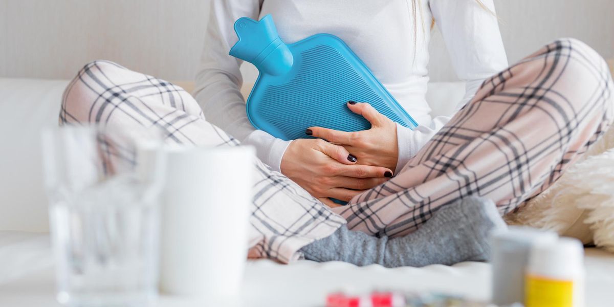 Woman with hot water bottle healing stomach pain