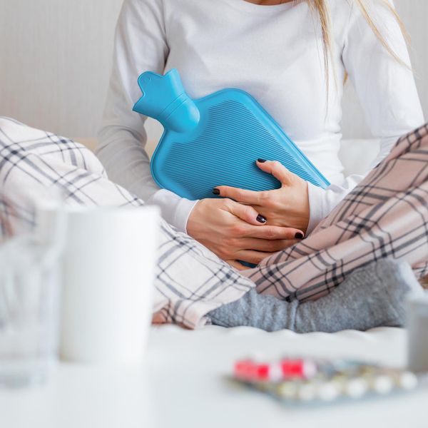 Woman with hot water bottle healing stomach pain