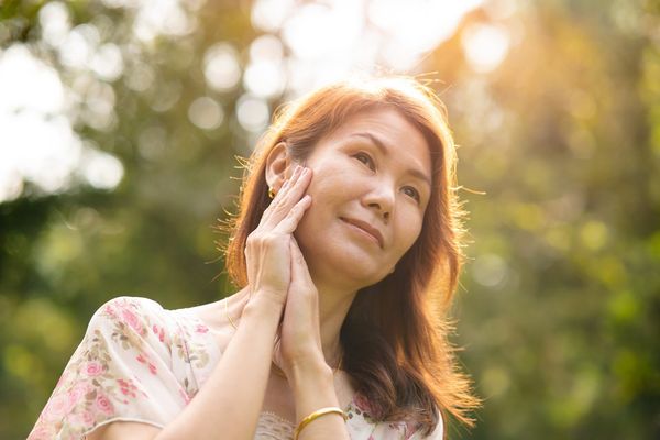 Woman with rare disease holding hands to face