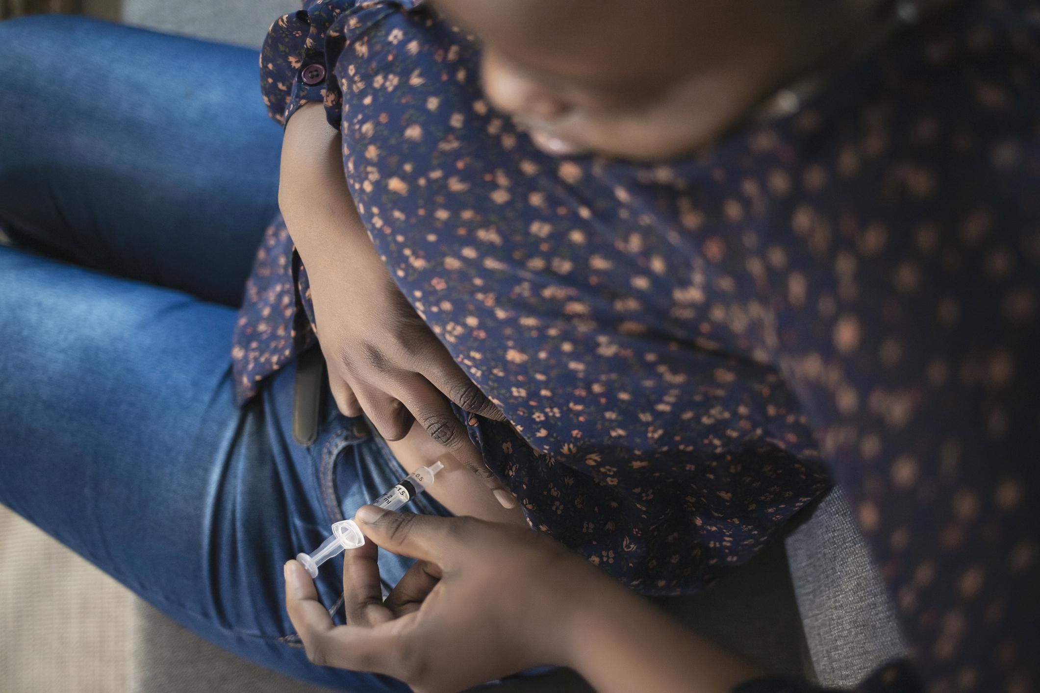 woman with syringe making insulin injections at abdominal skin