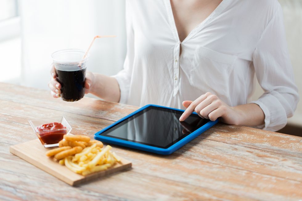 woman with tablet pc computer eating french fries with ketchup