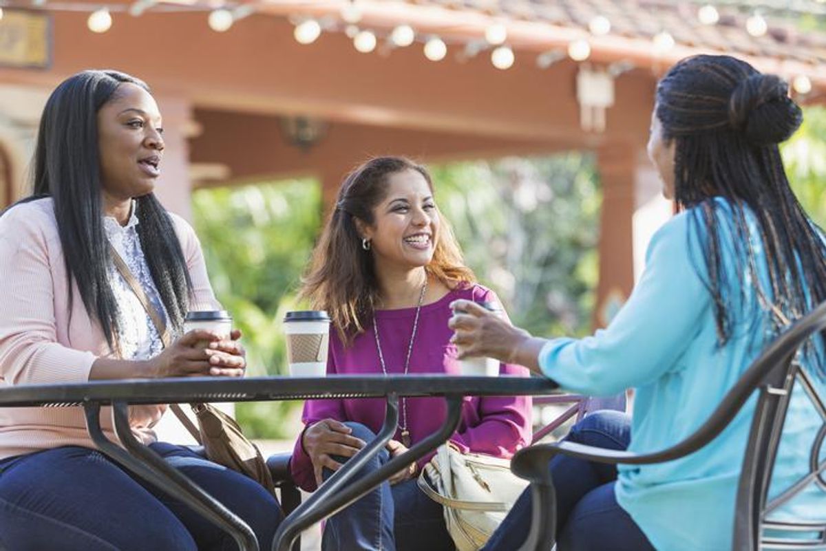 Women at sidewalk cafe talking, drinking coffee