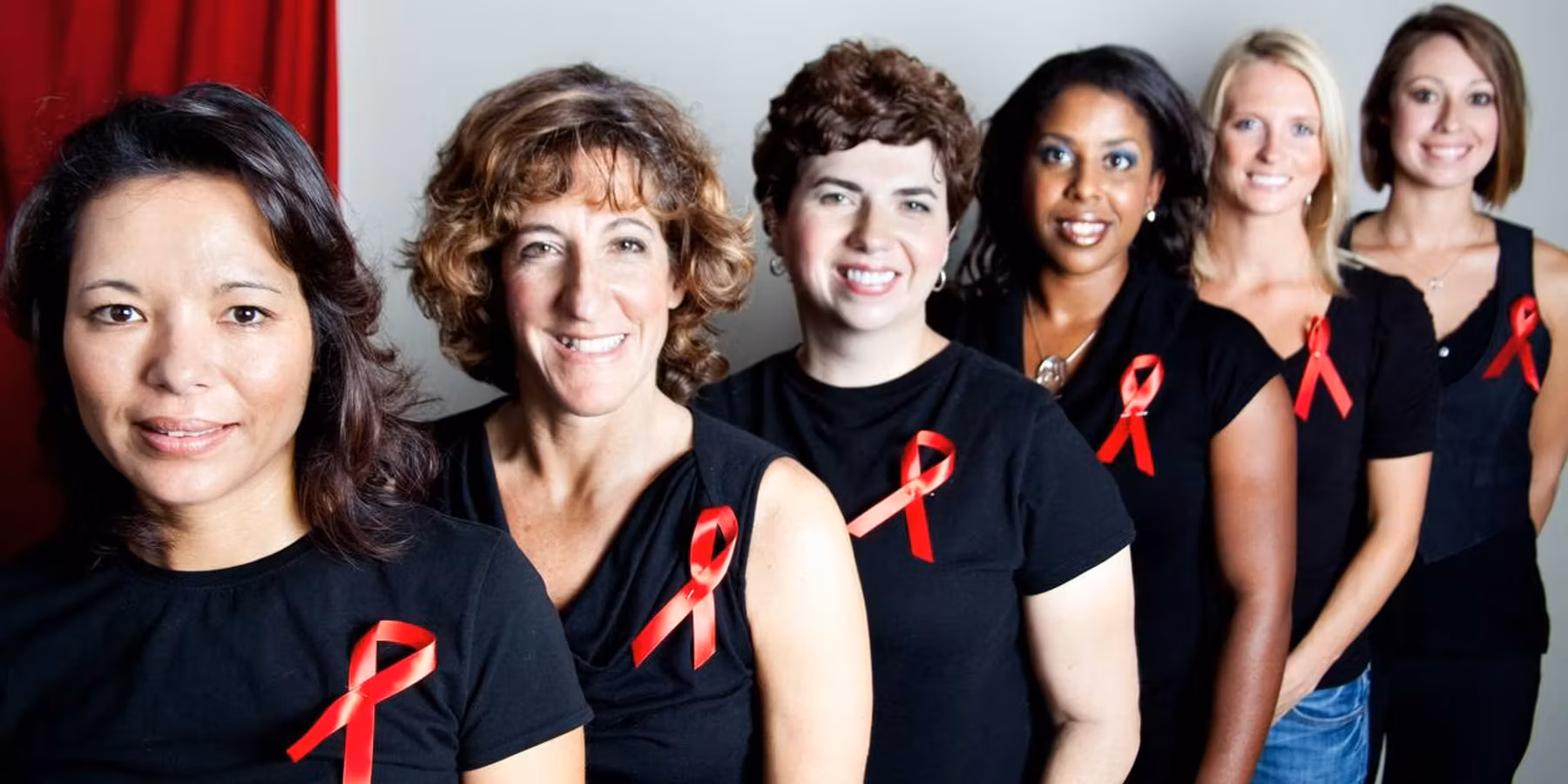 women wearing black shirts with aids awareness red ribbons