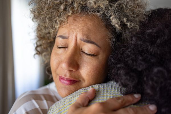 worried mid adult woman embracing her friend at home