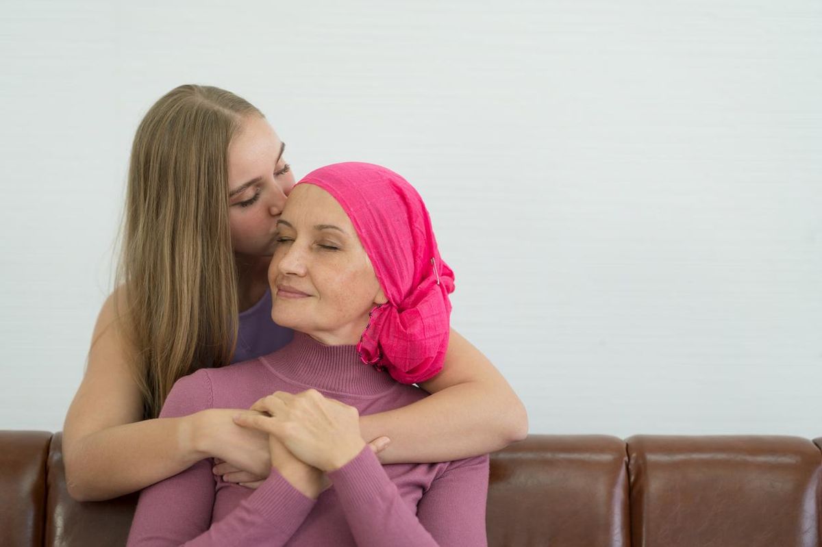 Young adult female cancer patient spending time with her daughter at home