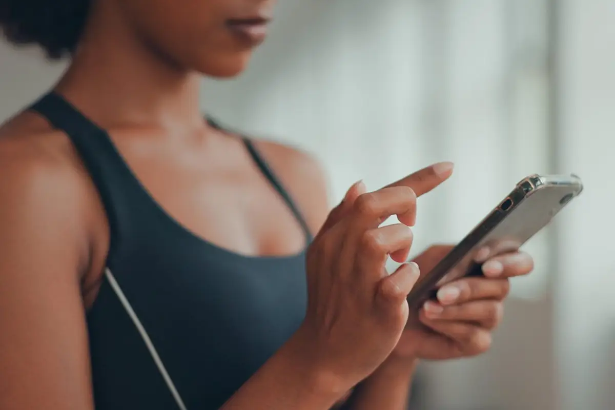 young African American sporty young woman, using yoga online fitness training application to get the workout plan