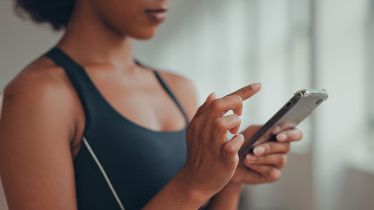 young African American sporty young woman, using yoga online fitness training application to get the workout plan