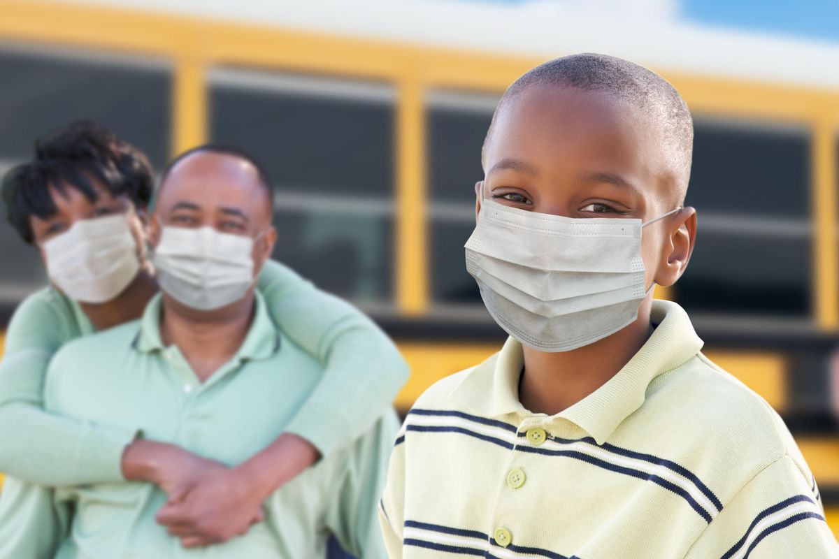 Young African American Student and Parents Near School Bus Wearing Face Masks