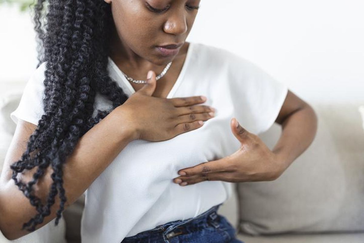 Young African American woman palpating her breast by herself