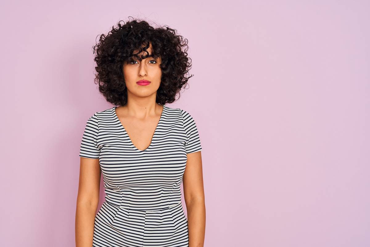 Young arab woman with curly hair wearing striped dress