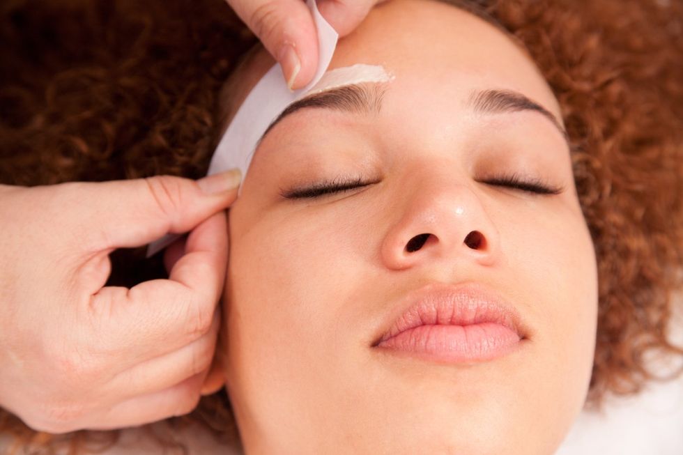 young bi-racial female having her eyebrows waxed.