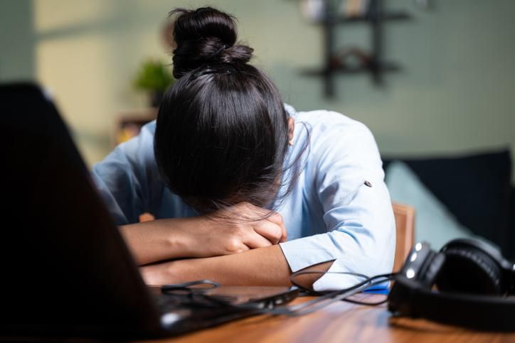 Young businesswoman sleeping by closing laptop while working