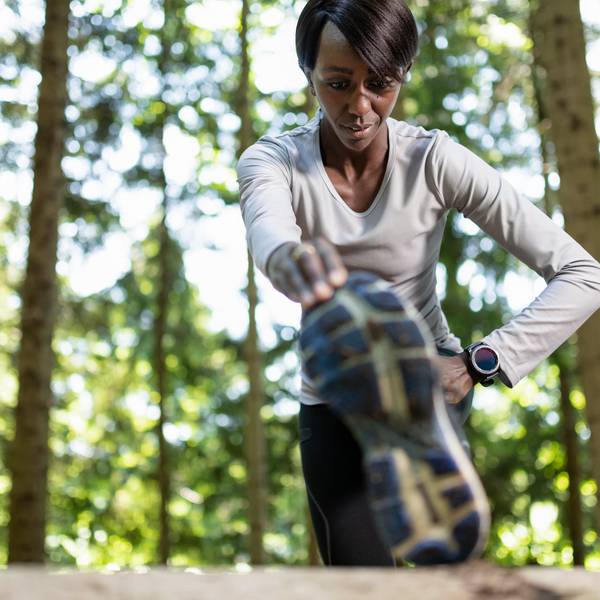 Young female runner warming up before running in forest