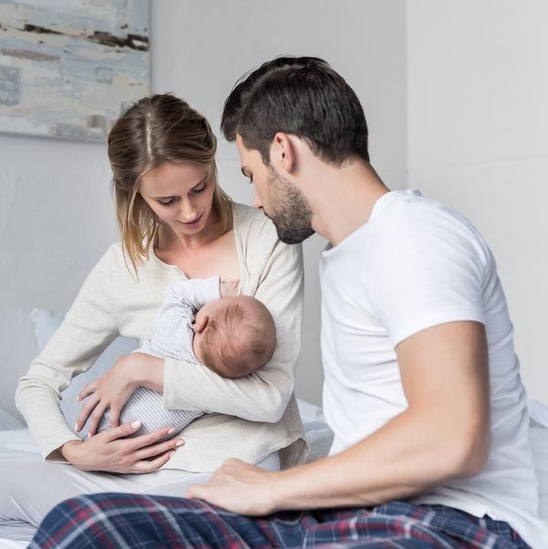 young husband looking how mother feeding little baby