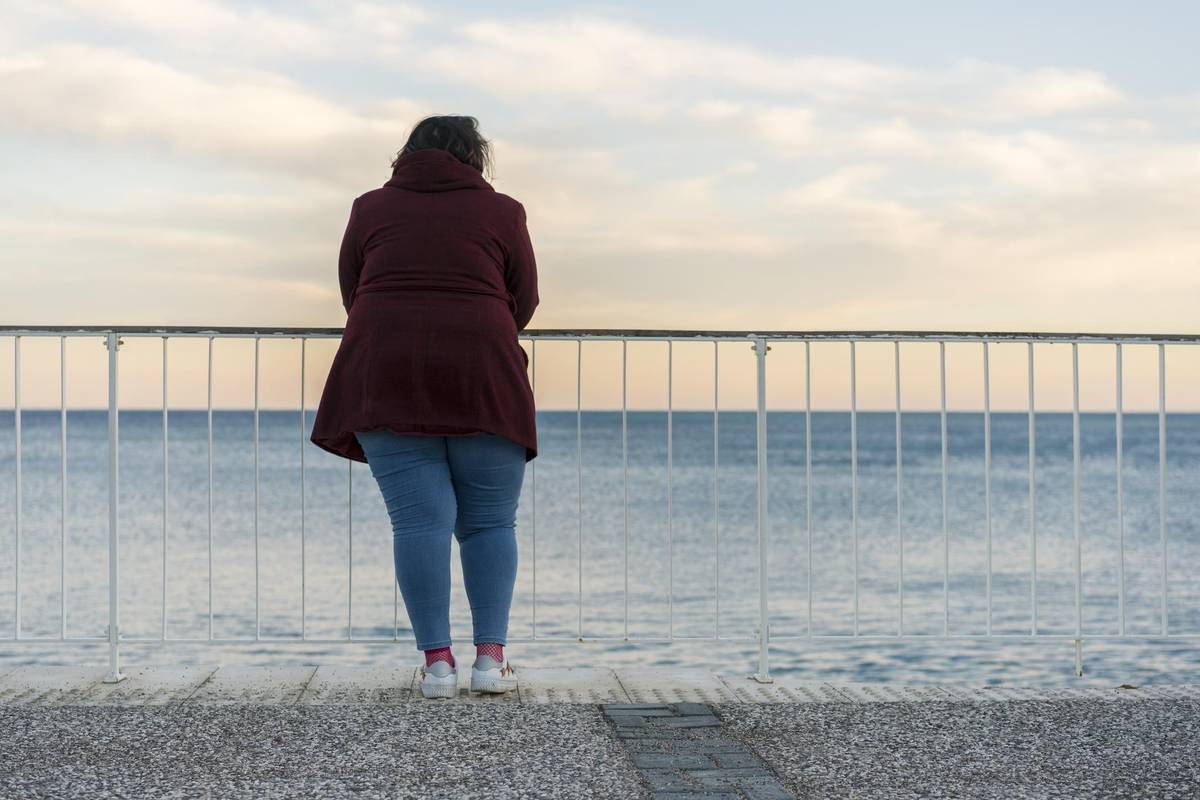 Young obese woman standing alone on the beach