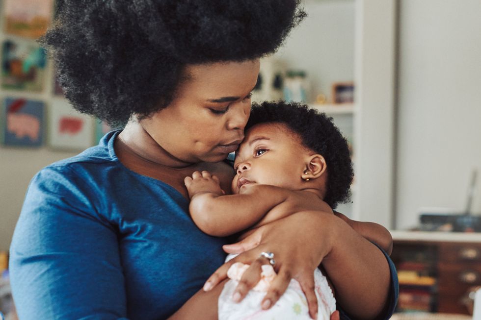 young woman cradling her adorable baby girl at home