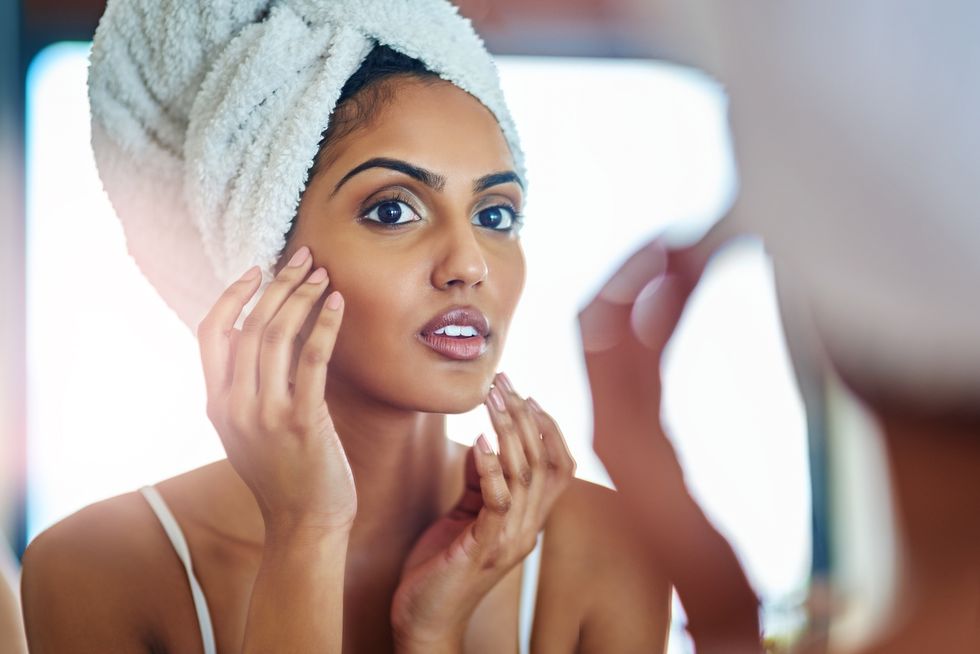 young woman inspecting her skin in front of the bathroom mirror