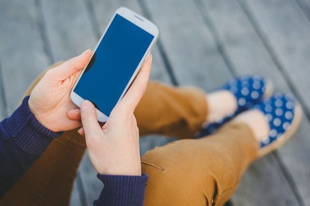 young woman sitting down look at her smartphone screen