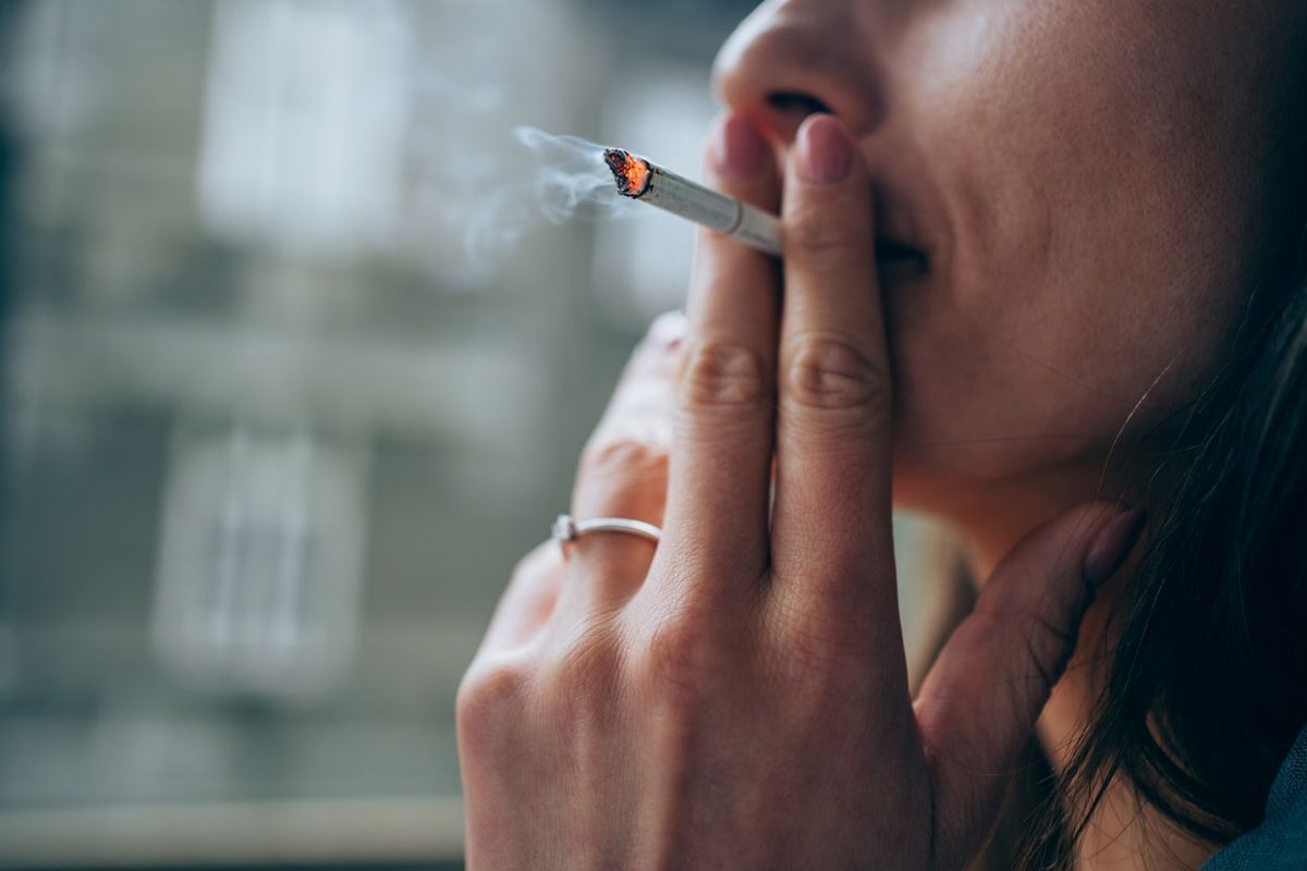 young woman smoking a cigarette outdoors