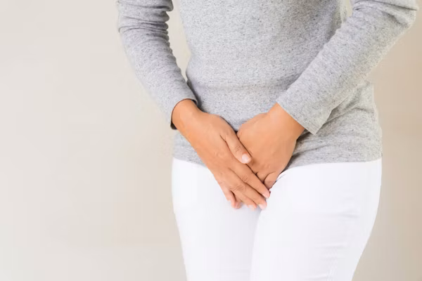 young woman suffering from overactive bladder, hands over her pelvic area