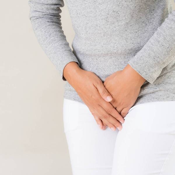 young woman suffering from overactive bladder, hands over her pelvic area
