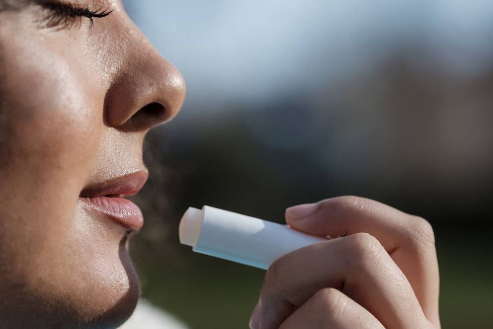 young woman using lip balm to moisture lips